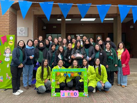 Un grupo de mujeres sonrientes celebra el Día Internacional del Juego con un marco colorido.