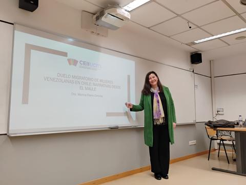 Una mujer presenta un tema sobre el duelo migratorio de mujeres venezolanas en una sala de conferencias.