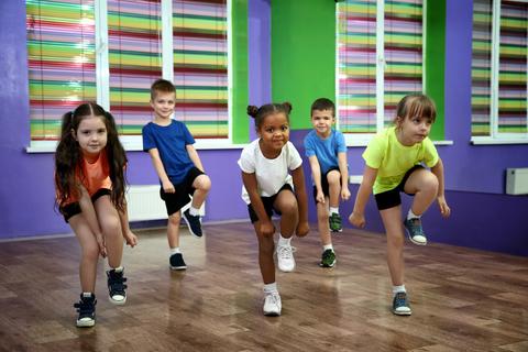 Un grupo de niños realizando una actividad de danza en un aula colorida.