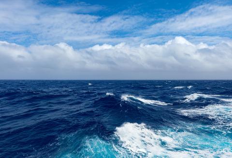 Un océano azul con olas y un cielo nublado en el fondo.