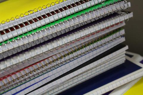 Una pila de cuadernos de diversos colores y tamaños apilados unos sobre otros.