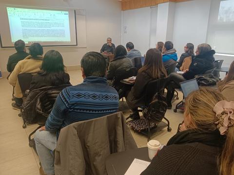 Un grupo de personas asiste a una charla en un aula.