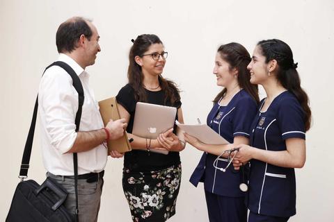 Un grupo de personas conversando en un ambiente académico con dispositivos electrónicos.