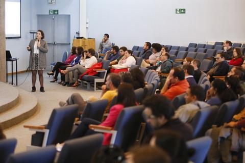 Una presentadora habla ante un público atento en un auditorio.