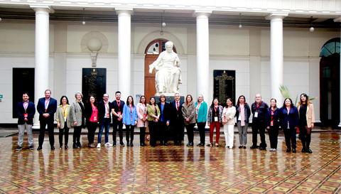 Un grupo de personas posando frente a una estatua en un vestíbulo con columnas.