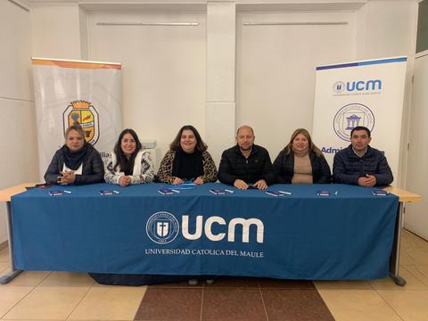 Grupo de personas sentadas detrás de una mesa con el logo de la Universidad Católica del Maule.