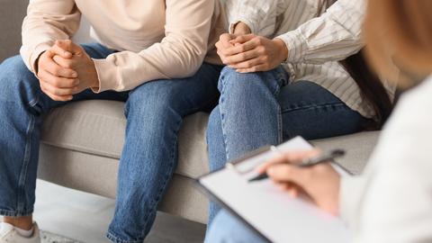 Pareja en sesión de terapia, mostrando tensión y apoyo mutuo.