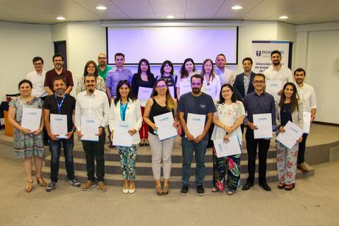 Un grupo de personas sonrientes sosteniendo certificados en un evento.