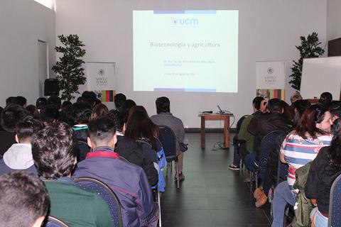 Una conferencia sobre biotecnología y agricultura con una audiencia sentada en un salón.