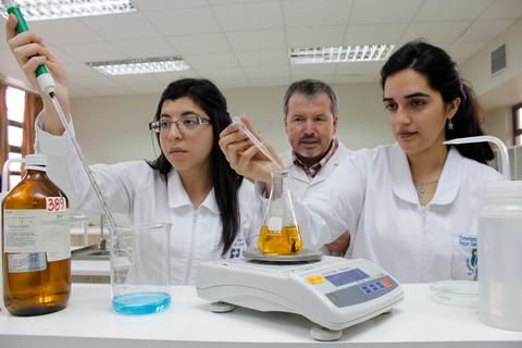 Tres personas realizan experiencias científicas en un laboratorio.
