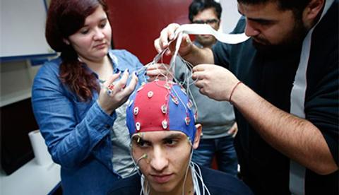 Un grupo de personas coloca electrodos en la cabeza de un joven para realizar un estudio de electroencefalograma.