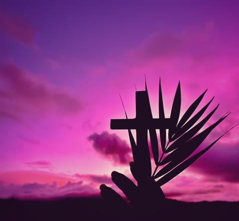 Una cruz y una palma se dibujan en un atardecer morado.