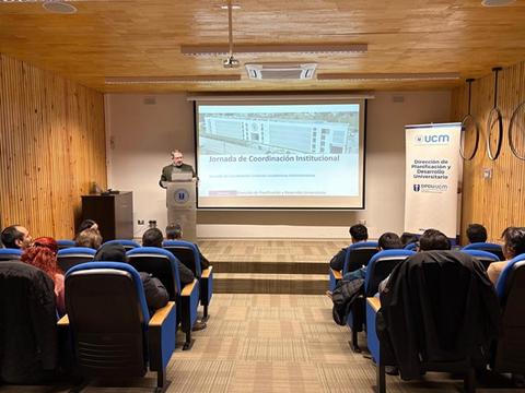 Un grupo de personas asiste a una charla sobre coordinación institucional en una sala de conferencias.