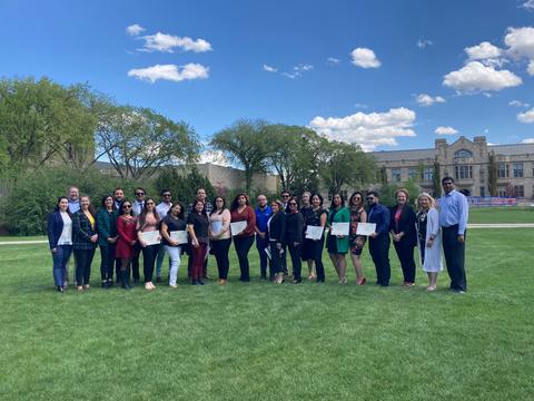 Grupo de personas posando en un parque con un cielo despejado y nubes.
