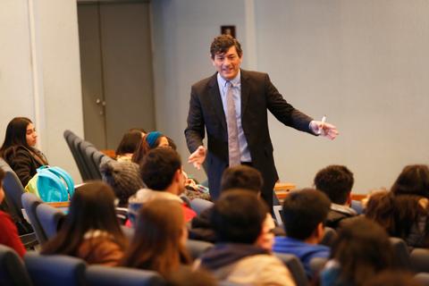 Un profesor está hablando frente a un grupo de estudiantes en un aula.