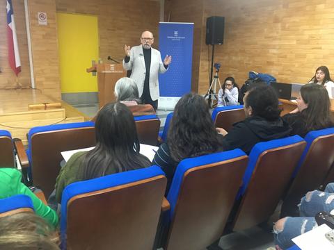 Un conferencista se dirige a una audiencia en un salón de actos.