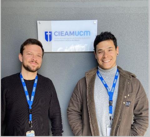 Dos personas están posando frente a un letrero que dice CIEAMUCM.