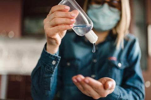 Una persona usando desinfectante de manos mientras lleva puesta una mascarilla.