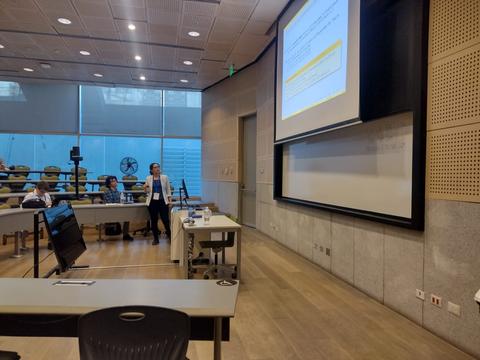 Una persona presenta en un aula moderna con alumnos atentos.