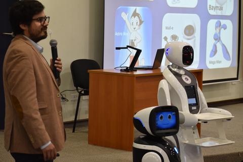 Un hombre presenta un robot en una charla sobre tecnología.