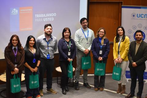 Un grupo de personas sonrientes posando en un evento con bolsas verdes.
