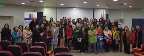 Un grupo grande de personas posando juntas en un auditorio.