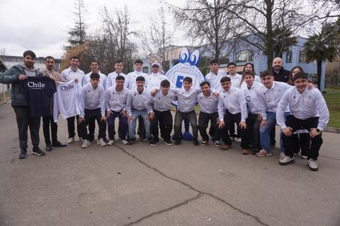 Un grupo de jóvenes posando sonrientes con camisetas blancas y un banner, mostrando orgullo chileno.