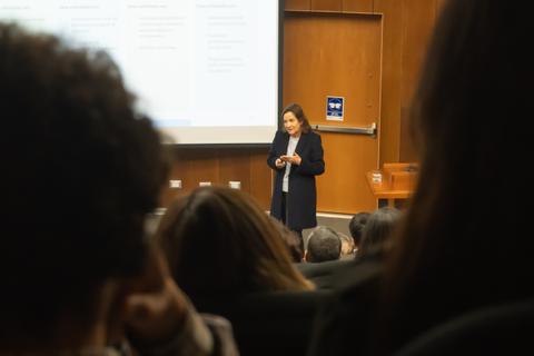 Una mujer está dando una charla frente a un auditorio lleno de gente.