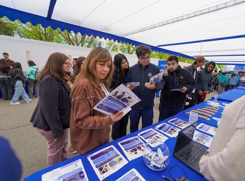 Un grupo de personas en un evento comunitario revisando información en un stand.