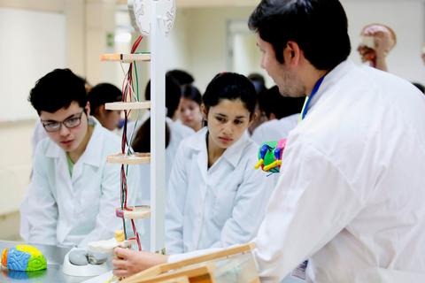 Un grupo de estudiantes en un laboratorio observando una demostración sobre el cerebro.