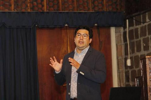 Un hombre gesticula mientras habla en una presentación.