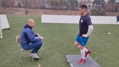 Un entrenador evalúa el rendimiento de un jugador en un campo de fútbol.