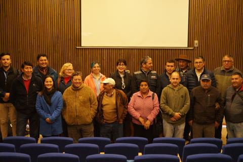 Grupo de personas posando en un auditorio con asientos azules.