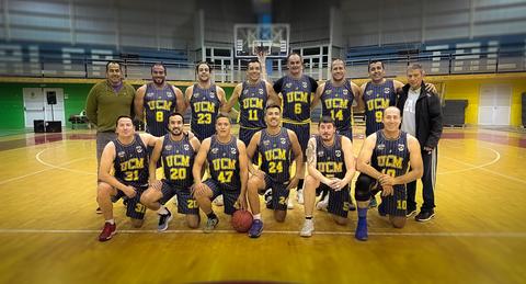 Un equipo de baloncesto posando en una cancha deportiva.