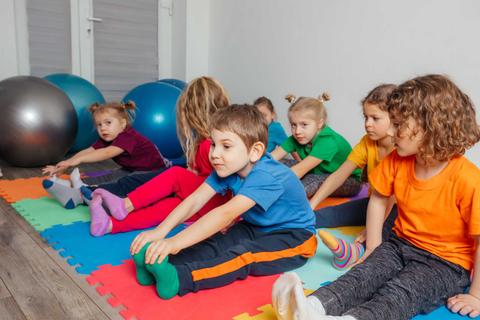 Niños haciendo ejercicios de estiramiento en una sala de actividades.