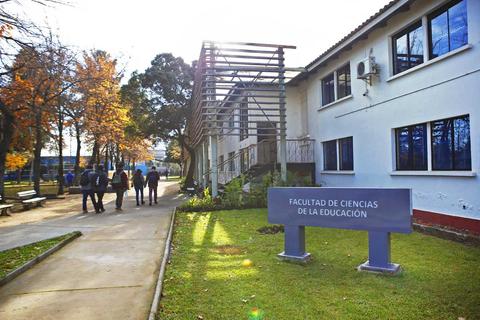 La imagen muestra la Facultad de Ciencias de la Educación rodeada de árboles y personas caminando.
