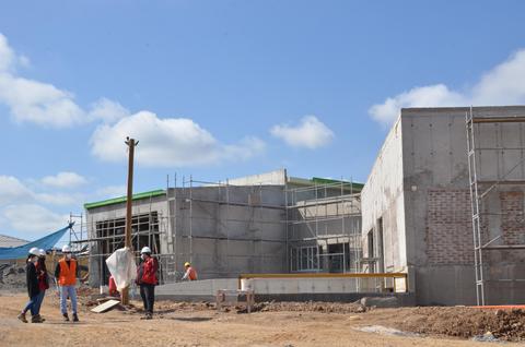 Un grupo de trabajadores supervisa la construcción de un edificio nuevo bajo un cielo despejado.