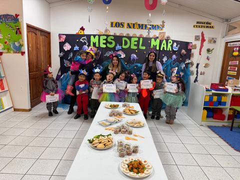 Celebración con niños y adultos en un evento temático sobre el mar, con decoraciones y comida en una mesa.