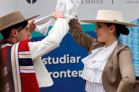 Dos personas vestidas con trajes tradicionales chilenos realizan una danza folclórica.