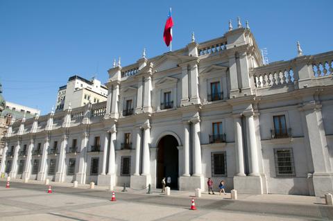 La imagen muestra la fachada del Palacio de La Moneda en Chile con la bandera del país ondeando.