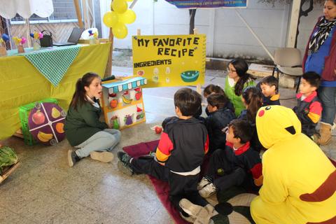 Una maestra está presentando una receta favorita a un grupo de niños entusiasmados en un ambiente festivo.
