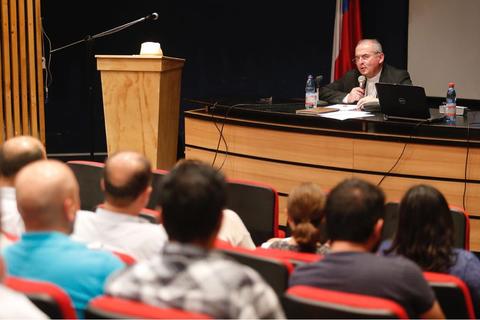 Un hombre habla frente a un grupo de personas en un salón de conferencias.