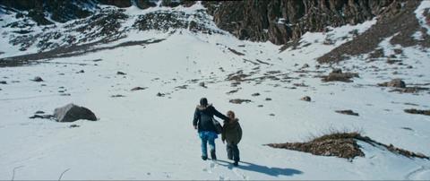 Una persona adulta y un niño caminan juntos por un paisaje nevado montañoso.