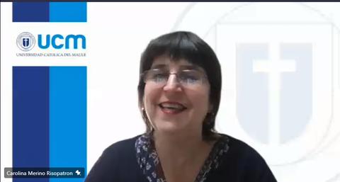 Una mujer sonriente se encuentra frente a un fondo con el logo de la Universidad Católica del Maule.