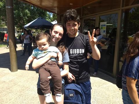 Un grupo de tres personas posando para una foto al aire libre, con un niño en brazos.