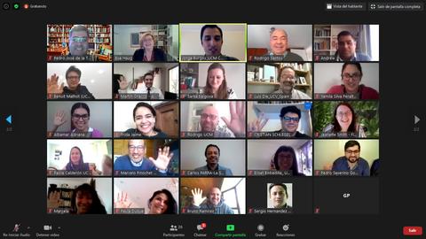 Un grupo de personas sonrientes en una videoconferencia, saludando con la mano.