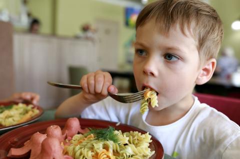 Un niño saboreando un plato de pasta con salchichas en forma de pulpo.