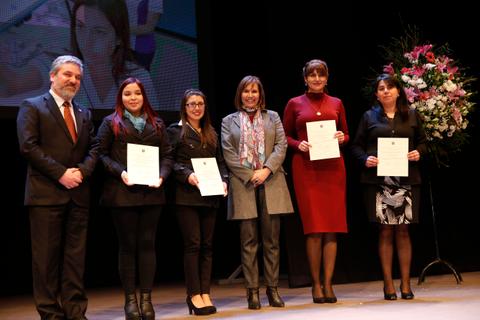 Un grupo de personas sonrientes sostiene certificados en un evento formal.