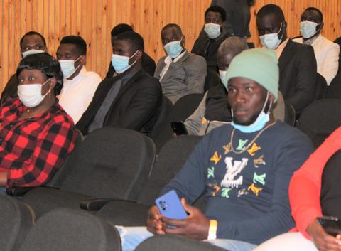 Un grupo de personas sentadas en un auditorio, muchas de ellas usando mascarillas.