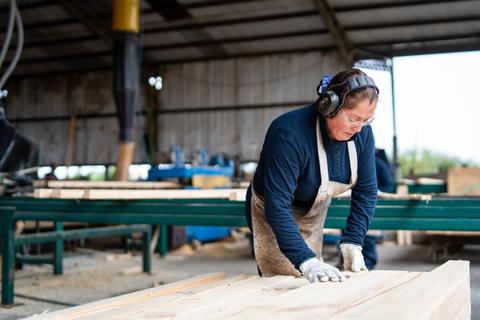 Un trabajador en un taller de madera, enfocado en su tarea de carpintería.